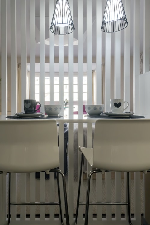 Elegante comedor en la Suite Catedral de Burgos con dos sillas, mesa, cubertería negra, lámparas colgantes y amplio espacio