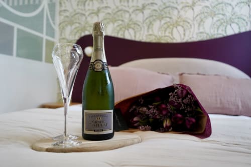 Bouteille de champagne et verre sur le lit du gîte La Maison D'olivier à Mesnard La Barotière