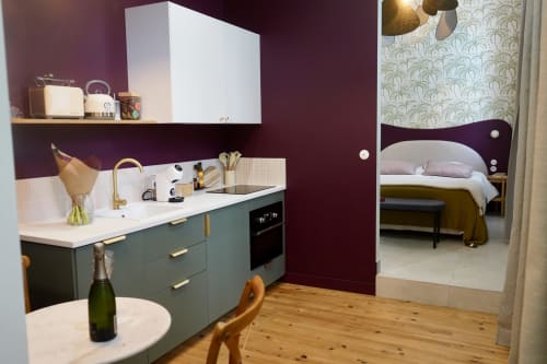 Petite cuisine contemporaine aux armoires bleu-canard et murs bordeaux, ouvrant sur la chambre à La Maison D'olivier, gîte en France