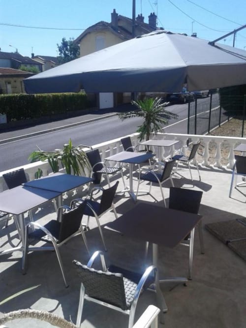 Terrasse extérieure de l'Hôtel de Champagne avec chaises et tables bleues et blanches, structure d'ombrage à Saint-Dizier