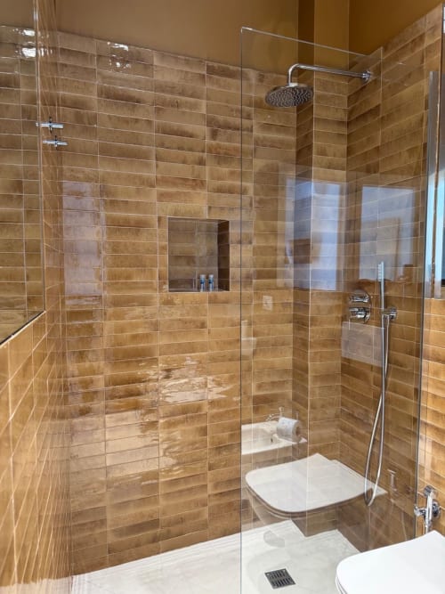 Bagno moderno con doccia a filo pavimento rivestita in ceramica color legno, box doccia in vetro, soffione pioggia e wc a Tresette Porta