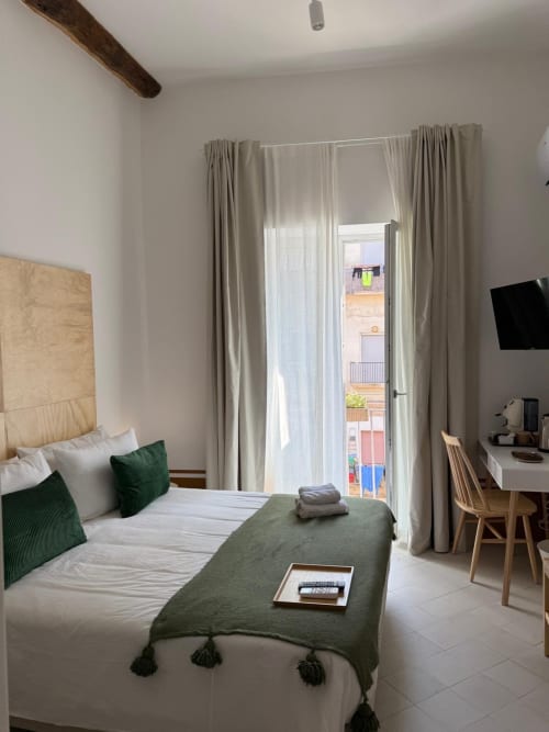 Camera luminosa presso Tresette Porta Capuana Napoli con letto queen, accenti verdi, balcone con vista città, scrivania e TV