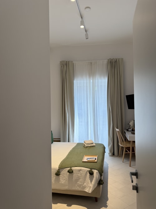 Camera moderna dell'hotel Tresette Porta Capuana a Napoli con letto, plaid verde, tende da pavimento a soffitto, area studio