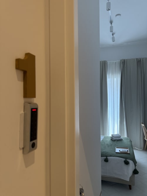Ingresso della camera d'hotel con serratura elettronica al Tresette Porta Capuana di Napoli, con letto, panchetta verde e tende
