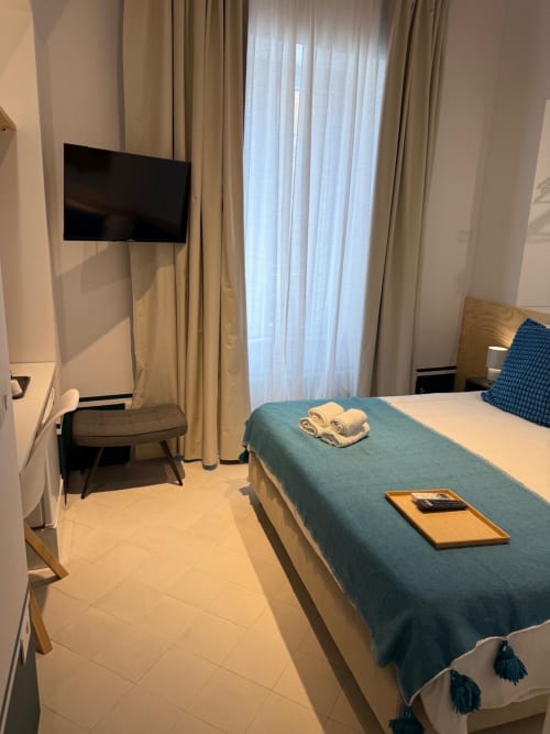 Camera moderna dell'Hotel Tresette Porta Capuana a Napoli con letto, TV a schermo piatto e vista su un monumento cittadino