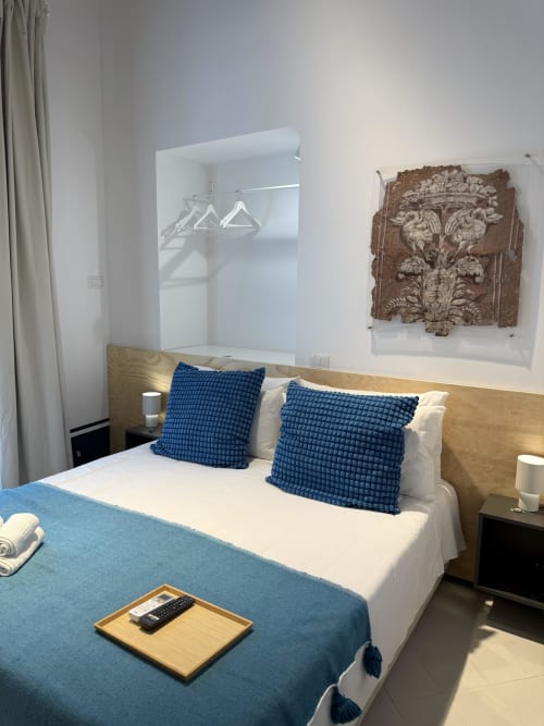 Camera moderna all'hotel Tresette Porta Capuana a Napoli con cuscini blu, testata in legno, specchio e decorazioni murali raffinate