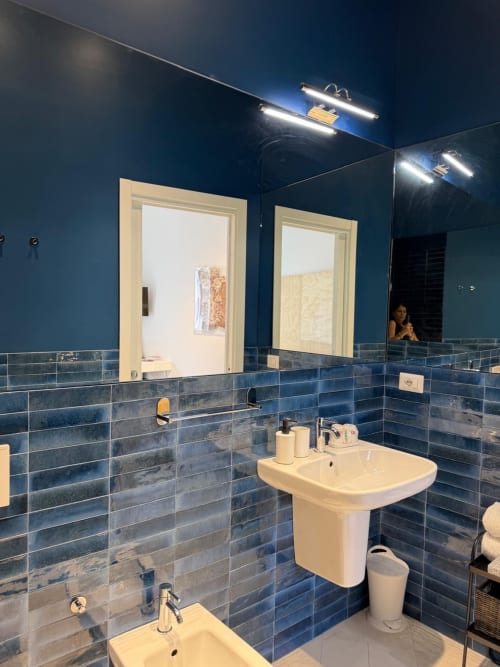 Bagno moderno con piastrelle blu presso Tresette Porta Capuana Napoli, doppi lavandini, specchi illuminati e finiture contemporanee