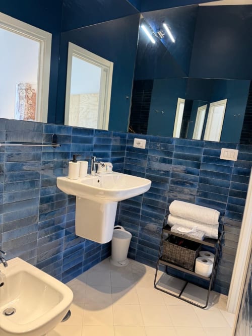 Bagno moderno blu con lavabo su colonna, pareti piastrellate e portasciugamani bianco presso Tresette Porta Capuana Napoli