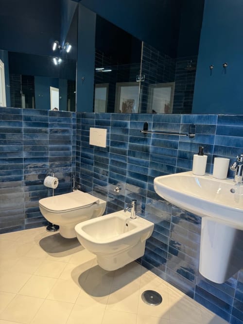 Bagno moderno con piastrelle blu, sanitari bianchi, bidet, wc e doppio lavabo all'hotel Tresette Porta Capuana di Napoli