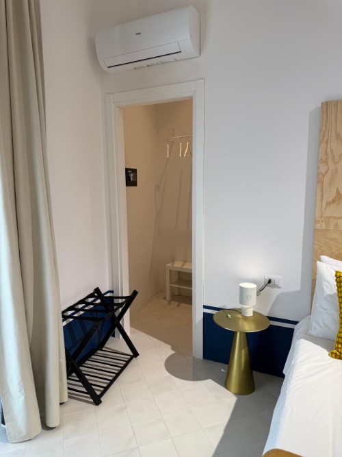 Camera moderna a Tresette Porta Capuana a Napoli con pareti bianche, finiture blu, portabagagli, tavolino dorato e