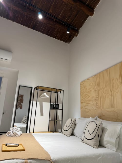 Camera moderna dell'hotel Tresette Porta Capuana a Napoli con letto in legno, biancheria bianca e cuscini decorativi
