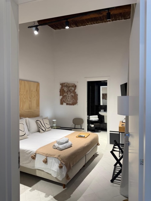 Camera moderna dell'hotel Tresette Porta Capuana a Napoli con letto bianco, testiera in legno, biancheria beige e bagno privato