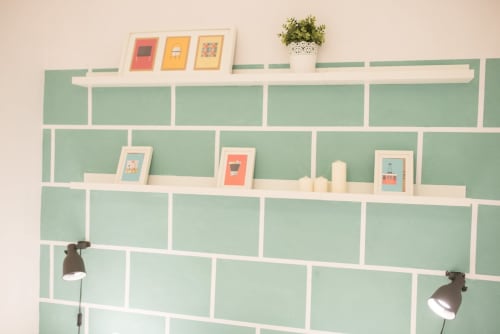Estantería de pared en apartamento moderno de Barcelona con diseño de rejilla verde menta, cuadros, planta en maceta e iluminación de trabajo