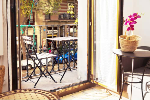 Vista del balcón del apartamento de Barcelona con orquídea rosa en la mesa y zona de descanso al aire libre