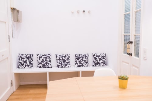 Luminoso comedor de apartamento barcelonés con mesa de madera, asiento integrado, cojines con patrón blanco y negro