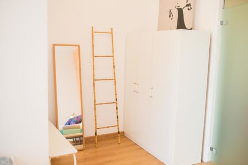 Interior de apartamento en Barcelona con escalera de madera, paredes blancas y amueblamiento minimalista en sala de estar