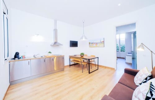 Apartamento moderno en Barcelona con cocina abierta, comedor, suelos de madera y sala de estar con sofá burdeos