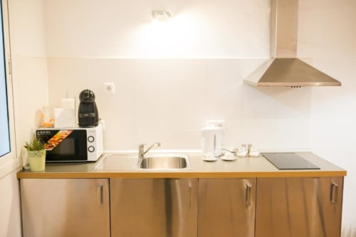 Cocina moderna en apartamento de Barcelona con electrodomésticos de acero inoxidable, fregadero, estufa y gabinetes blancos