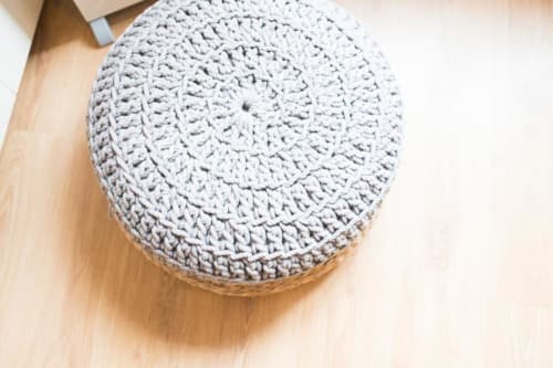 Puf gris tejido a crochet en el piso de madera de la sala de estar de un apartamento en Barcelona