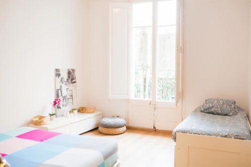Dormitorio luminoso en apartamento de Barcelona con vista a la ciudad, cama de madera, escritorio blanco y mobiliario moderno