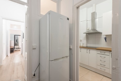 Cocina moderna de apartamento en Barcelona con refrigerador blanco, estufa y encimeras de madera