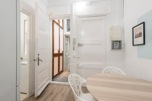 Pasillo de apartamento moderno en Barcelona con puertas blancas, mesa de madera y entrada al baño con ducha de cristal