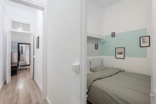 Pasillo de apartamento moderno en Barcelona con pared de acento verde menta, cama queen, obras de arte enmarcadas y corredor de paredes blancas