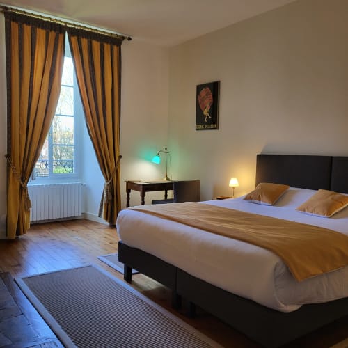 Chambre élégante aux rideaux dorés, lit noir et lumière chaleureuse à Logis des Tourelles B&B à Cognac