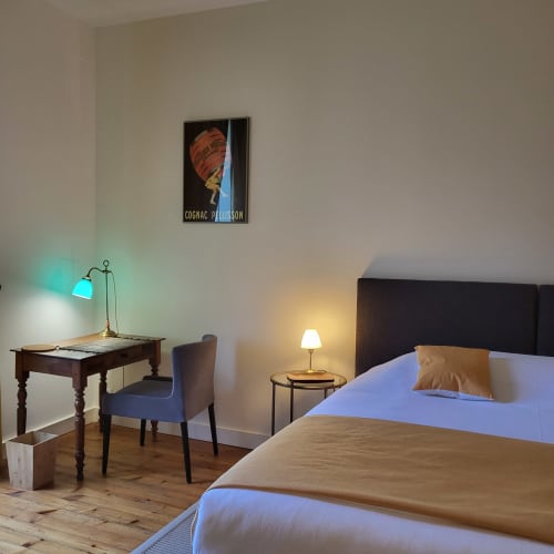 Chambre moderne au Logis des Tourelles B&B à Cognac avec bureau, chaise et affiche vintage Cognac Palisson
