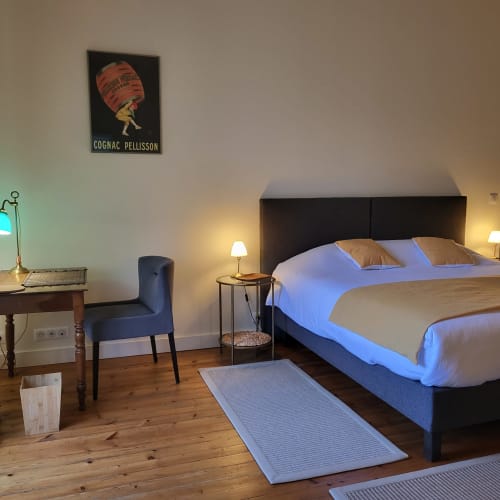 Chambre élégante du Logis des Tourelles B&B à Cognac avec tête de lit noire, linge bleu et cognac Pellisson vintage