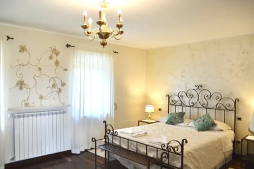 Le Rose bedroom at Agriturismo Colle Mura in Gualdo Tadino, Italy, with wrought iron bed and chandelier