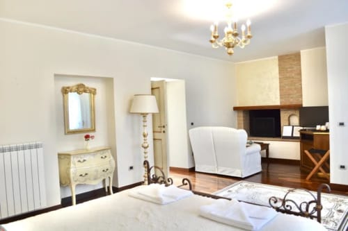 Elegant bedroom at Agriturismo Colle Mura in Gualdo Tadino, Italy, featuring ornate furnishings and fireplace