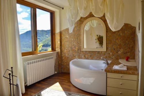Luxury bathroom at Agriturismo Colle Mura in Gualdo Tadino with soaking tub, mountain views, and classic decor