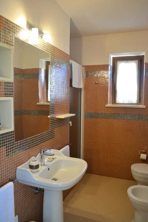 Modern bathroom at Agriturismo Colle Mura with orange mosaic tiles, pedestal sink, and walk-in shower in Le Rose room, Gualdo
