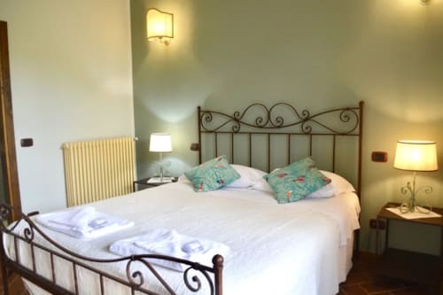 Il Glicine bedroom at Agriturismo Colle Mura, Gualdo Tadino - wrought iron bed with white linens and turquoise pillows