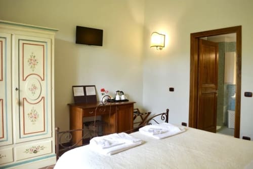 La camera Glicine presso l'Agriturismo Colle Mura a Gualdo Tadino - elegante camera da letto con biancheria bianca, mobili in legno