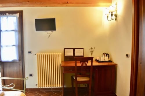 La camera Lavanda dell'Agriturismo Colle Mura a Gualdo Tadino presenta arredi in legno, pareti color crema, radiatore e stile rustico