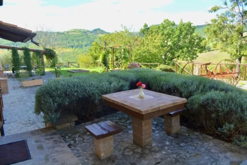 Tavolo in pietra circondato da piante di lavanda nel giardino dell'Agriturismo Colle Mura, Gualdo Tadino, Italia
