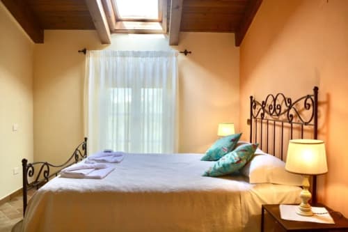 Bright bedroom with wrought iron bed, turquoise pillows, and warm lighting at Agriturismo Colle Mura in Gualdo Tadino