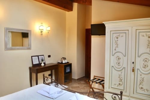 Camera accogliente ad Agriturismo Colle Mura a Gualdo Tadino con letto, scrivania, armadio decorativo e illuminazione calda
