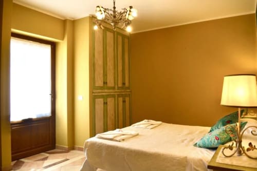 La camera L'Edera dell'Agriturismo Colle Mura a Gualdo Tadino, con pareti dorate, letto, armadio e lampada