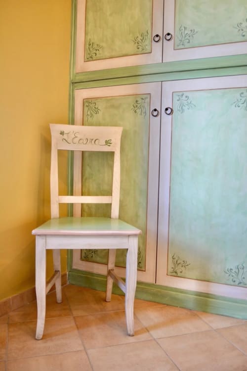 Sedia in legno bianco nella sala L'Edera di Agriturismo Colle Mura, Gualdo Tadino, con armadi verdi decorativi