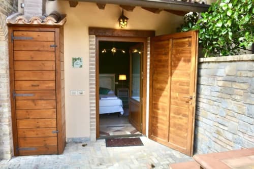 Ingresso della camera L'Edera all'Agriturismo Colle Mura di Gualdo Tadino, con portali in legno e cortile in pietra