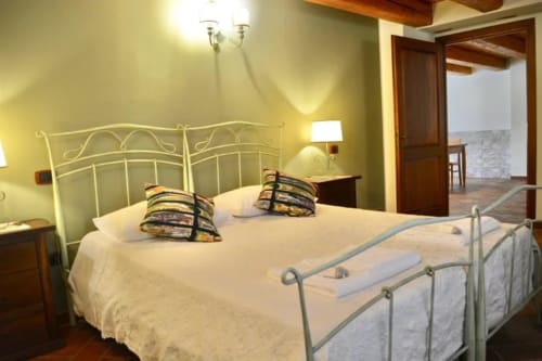 Spacious bedroom with wrought iron bed and cream bedding at Agriturismo Colle Mura in Gualdo Tadino, Italy