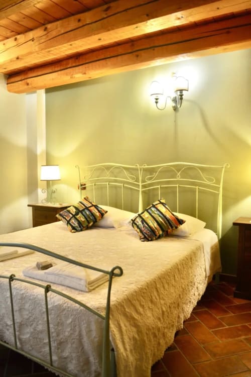 Il Noce accessible apartment bedroom at Agriturismo Colle Mura in Gualdo Tadino with wrought iron bed and wooden beams