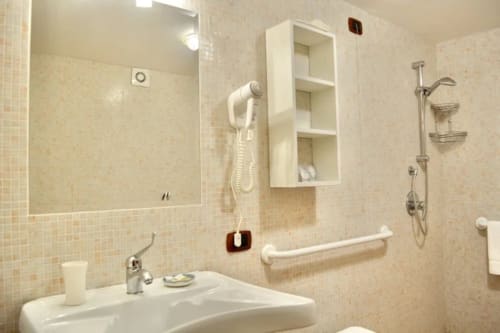 Accessible bathroom at Agriturismo Colle Mura with sink, grab bars, and walk-in shower in Gualdo Tadino, Italy