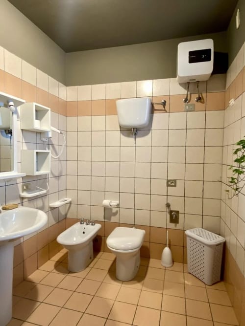 Bathroom with toilet, bidet, sink and tiled walls at Agriturismo Colle Mura, Gualdo Tadino, Italy