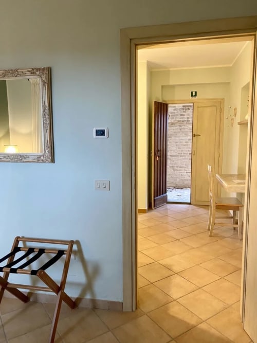 Le Campanule room at Agriturismo Colle Mura in Gualdo Tadino, Italy, showing entry with tiled floors and doorway to bedroom