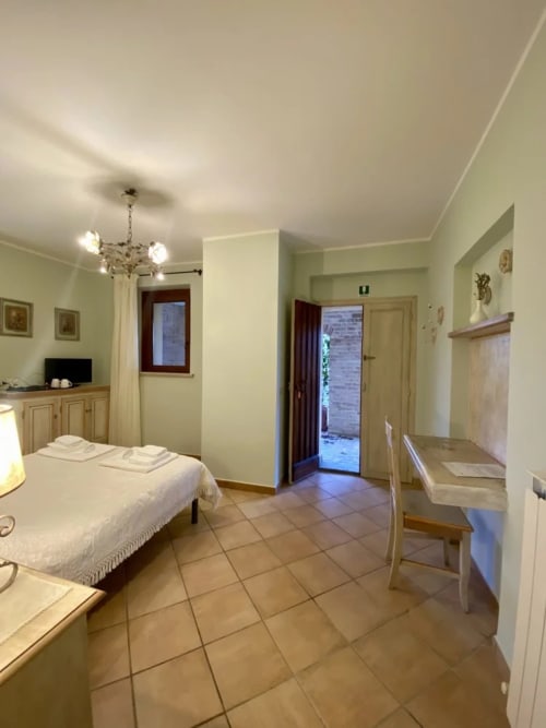 Le Campanule room at Agriturismo Colle Mura in Gualdo Tadino, Italy - spacious bedroom with bed, terracotta flooring, and
