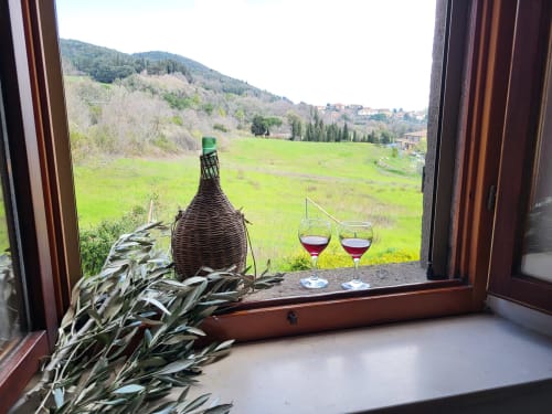 Veduta dalla finestra di I Castagnini B&B a Montecatini Val di Cecina con calici di vino e paesaggio della campagna toscana